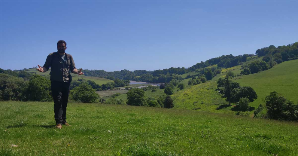 Ambios director Jack Skuse with our rewilding land behind