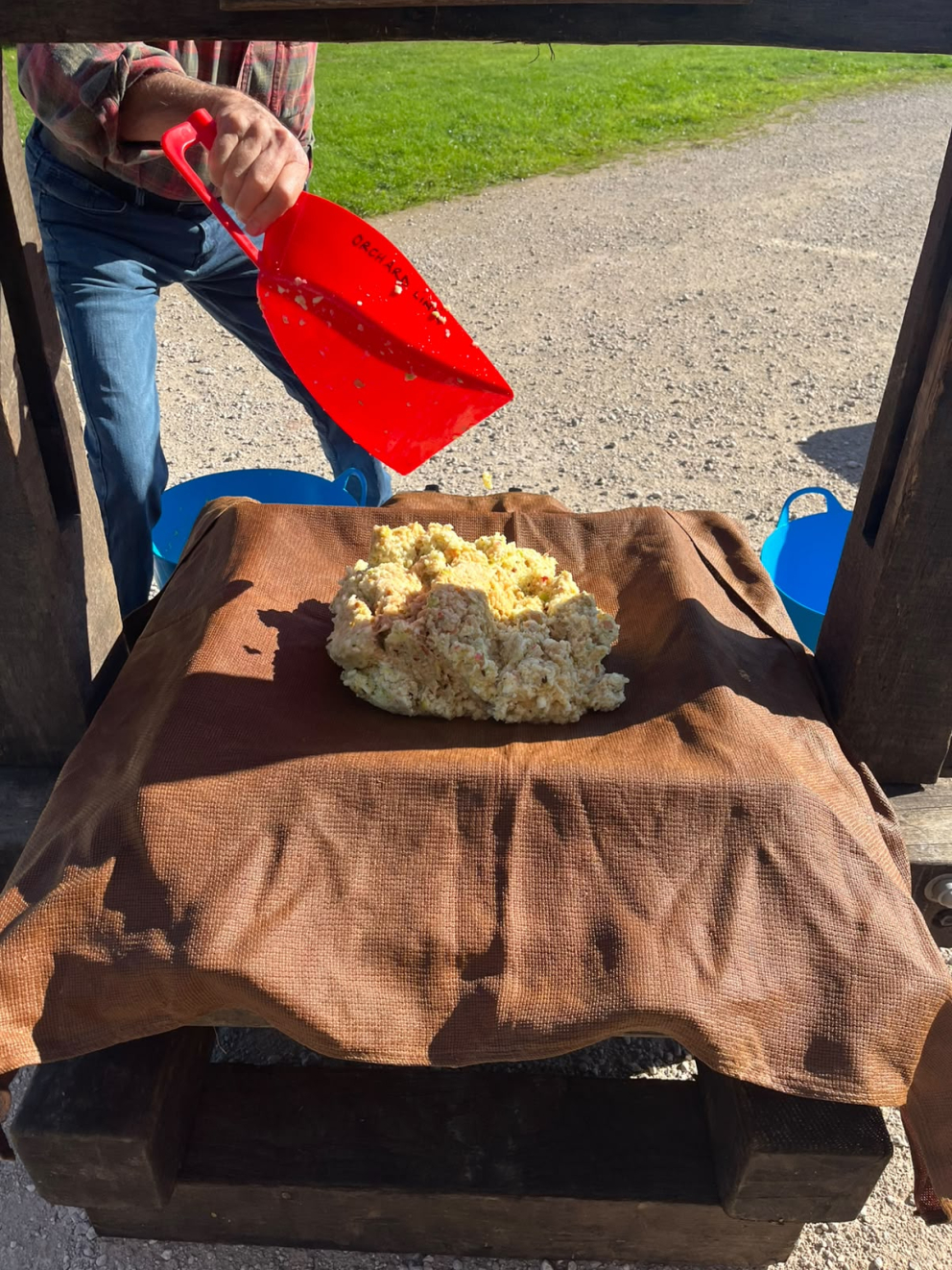 3. The scratted apple is spooned into sections of the apple press, to be wrapped in cloth and made into parcels. These parcels will be stacked on top of each other, then pressed together to squeeze out the juice.