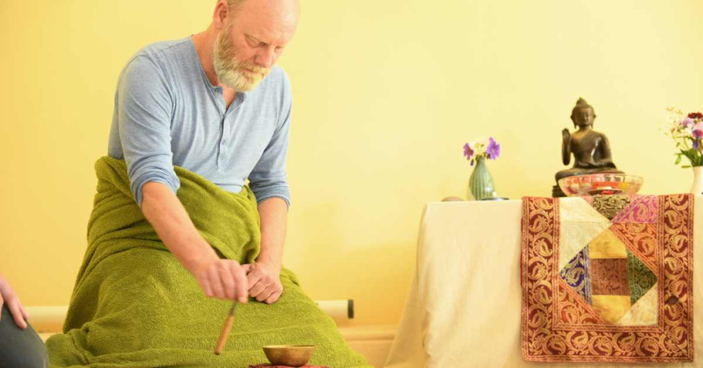 Barry Thurgood strikes the singing bowl at a meditation session in The Barn retreat centre at the Sharpham Trust