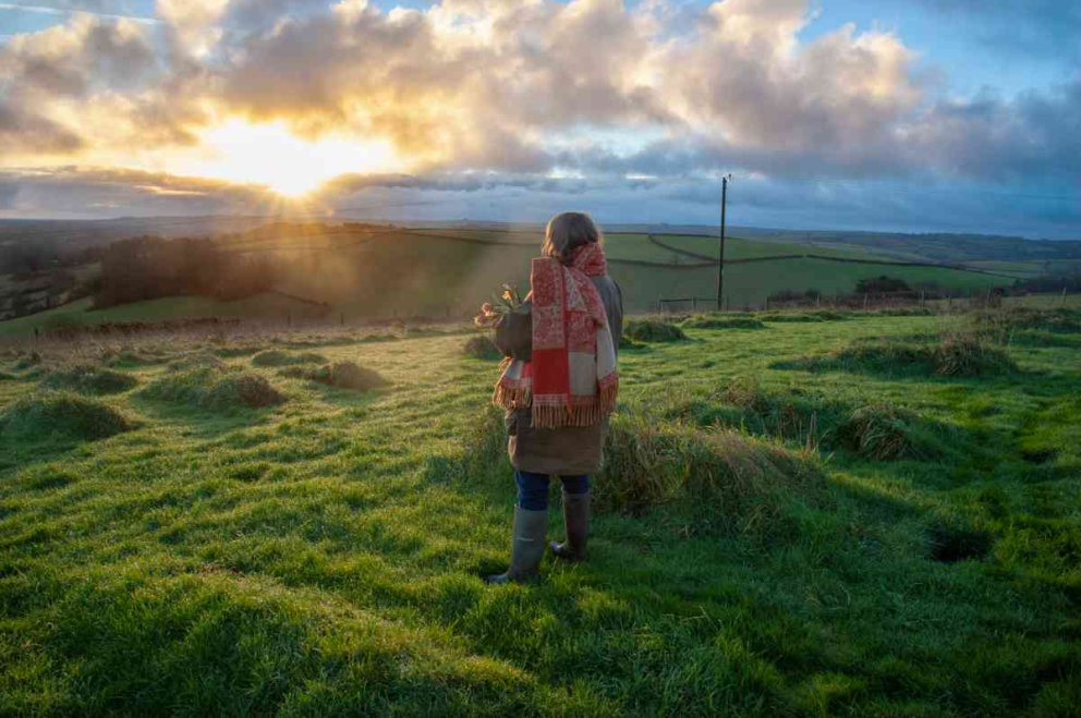 Author Sophie Pierce gazes into the sunrise at The Green Hill - Sharpham Meadow natural burial ground