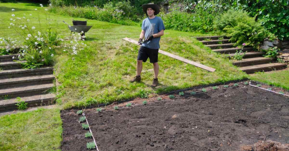 A Kickstart trainee plans and prepares the newly designed flowerbeds in the Percy Cane garden in June 2021