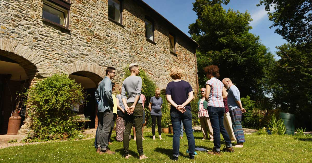 People in a ring outside The Barn Retreat at Sharpham
